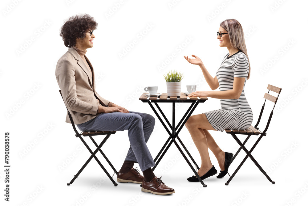 Young woman sitting in a cafe and talking to a young man - obrazy, fototapety, plakaty 