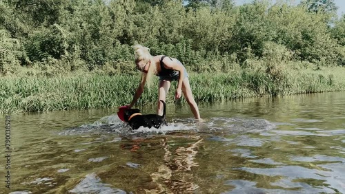 A woman and a dog playing with frisbee on the river