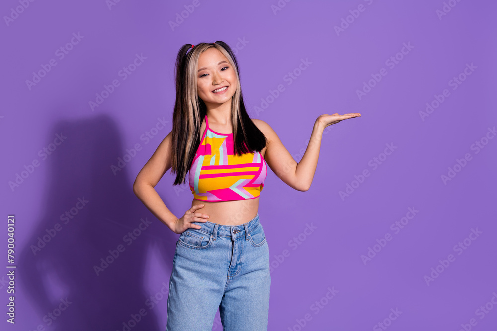 Photo of lovely cute girl wear stylish clothes arm hold empty space isolated on purple color background Photo of lovely cute girl wear stylish clothes arm hold empty space isolated on purple color background