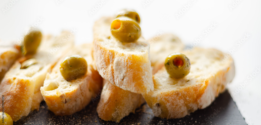 Baguette stuffed with olives, cut with fresh green olives and parsley, served on a stone plate Baguette stuffed with olives, cut with fresh green olives and parsley, served on a stone plate