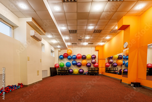 Empty spacious fitness room with fitballs against the wall and dumbbells on the floor photo