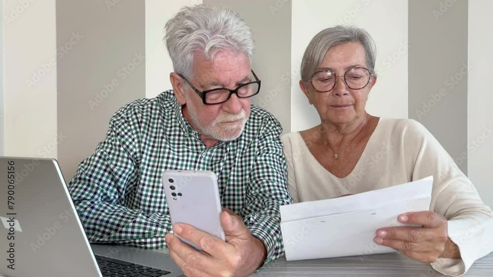 Video call concept. Elderly couple sitting at home talking remotely with doctor on mobile phone webcam to communicate the results of some medical tests waits for doctor's consultation