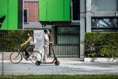 Cheerful woman riding a bicycle crosses a concentrated man on an electric scooter through the city photo