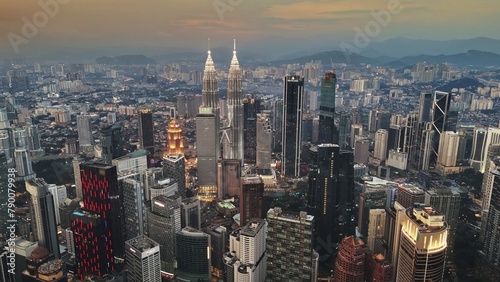 Aerial evening shot of Kuala Lumpur city center at sunset, Malaysia. Flying over illuminated skyscrapers and hills in the background in Kuala Lumpur