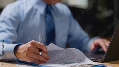 Businessman manager is sitting at a desk with a laptop and a pen. He is writing on a piece of paper