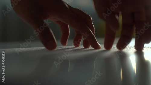 Close up hand of a blind person reading some braille text on page paper to learn. Finger of blind student touching the braille alphabet Code on sheet. Disabled person concept. photo