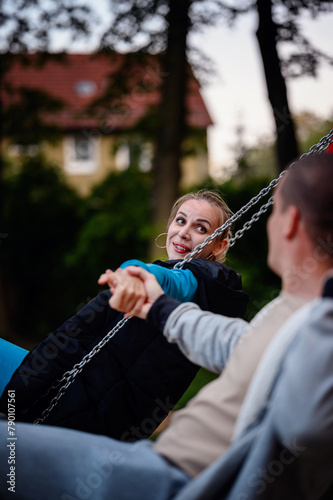 A close-up captures a woman's joyful expression as she swings, holding hands with a companion, with the soft focus adding intimacy to the moment