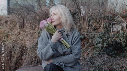 An elegant mature woman with flowers on the bench
