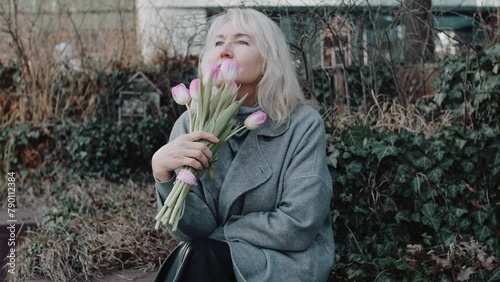 An elegant mature woman with flowers on the bench