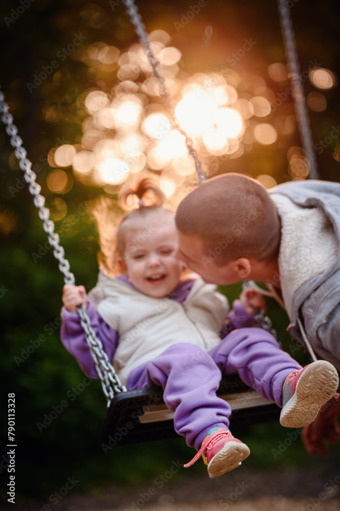 Heartwarming laughter fills the air as a toddler gleefully swings towards her parent, encapsulating the pure joy of a playful moment Heartwarming laughter fills the air as a toddler gleefully swings towards her parent, encapsulating the pure joy of a playful moment