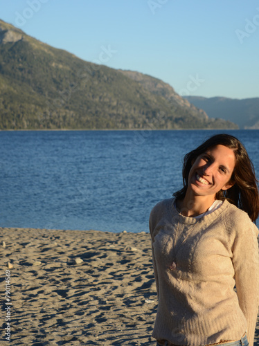 portrait of Latin American brunette woman, with lake and mountains background on vacation enjoying the place
