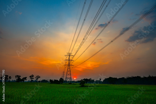 Silhouette street light post, electric pole and high voltage tower.High voltage transmission pole against evening sunset sun background.
