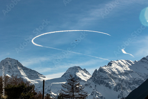 Curved Chemtrail above snowy mountains Swiss Alps Switzerland