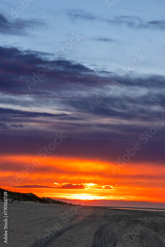 Beautiful golden hour beach sunset with glowing sun and colorful sky shows vibrant colors as north sea sand dunes and nature reserve at the ocean in golden hour sunshine as travel destination agents