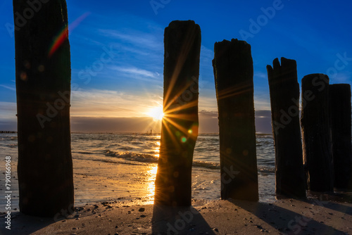 Beautiful golden hour beach sunset with glowing sun and colorful sky shows vibrant colors as north sea sand dunes and nature reserve at the ocean in golden hour sunshine as travel destination agents