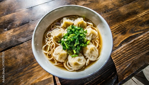 A bowl of wonton noodle with soup from a top angle on a beautiful wooden table photo