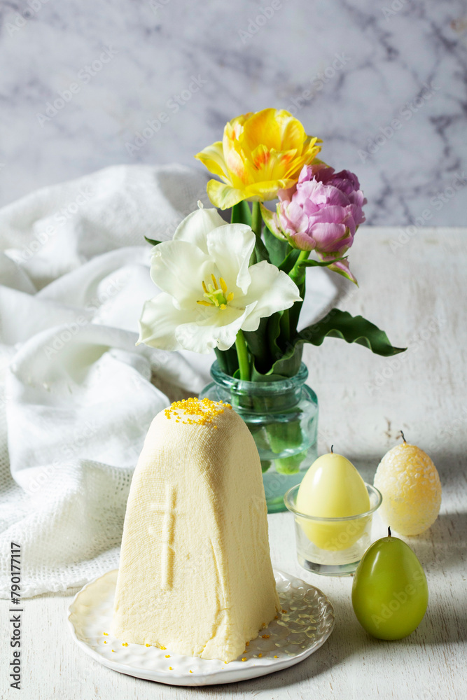 Traditional Slavic Easter dish made from cottage cheese - Paskha, a bouquet of tulips and candles on a light background.