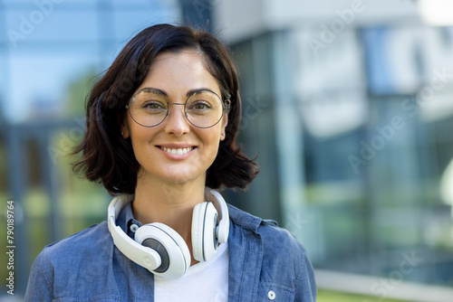 Confident student with headphones enjoying sunny day on campus