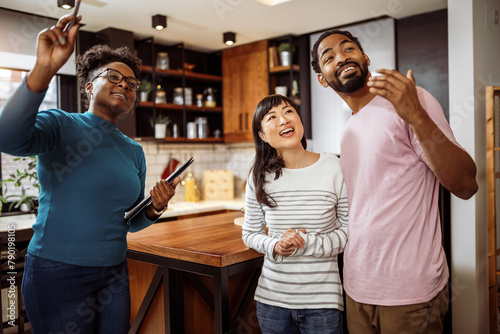 African American real estate agent showing house to multiracial couple, realtor telling clients about home advantages, interior designer discussing renovation ideas with homeowners.
