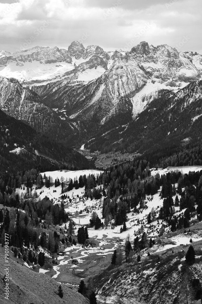 Monochrome Aufnahme einer südtiroler Landschaft mit weitem Blick in ein tief liegendes Tal hinein, mit massivem Bergpanorama im Hintergrund