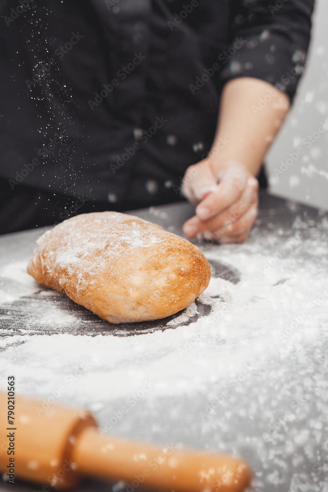 An experienced chef cooks in a professional kitchen prepares dough with flour for making ciabatta bread. An experienced chef cooks in a professional kitchen prepares dough with flour for making ciabatta bread.