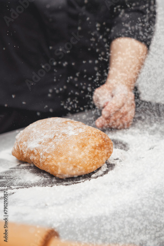 An experienced chef cooks in a professional kitchen prepares dough with flour for making ciabatta bread.