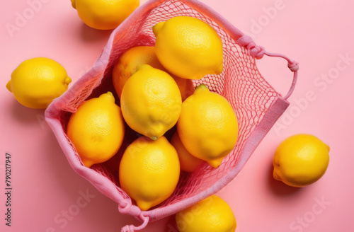 Fresh healthy lemons in a pink string cotton bag placed on pink background photo