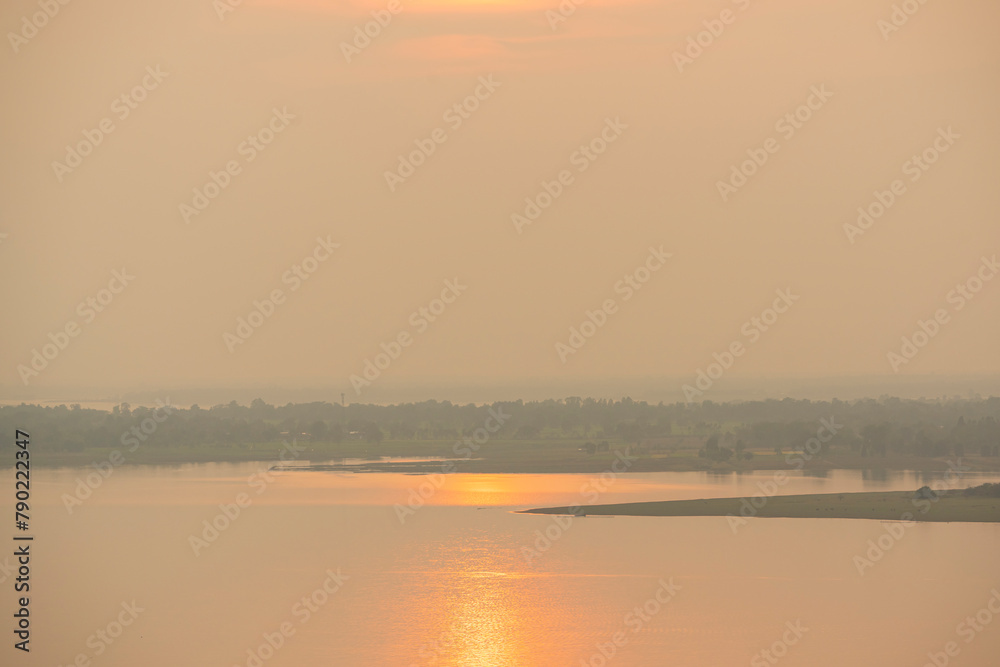 Sunlight reflected on the water surface.Dramatic golden sunset tropical sea background.Yellow sun sets behind the lake.Beautiful sunrise on the smooth wave.