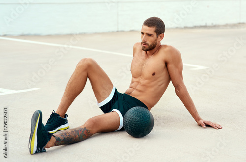 Male athlete, rest and body with medicine ball for sports, exercise and fitness on break. Healthy, man and topless in workout, cardio and wellness for muscle, strong and training for mental wellbeing