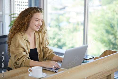 portrait young woman smiling and working on laptop computer in the office
