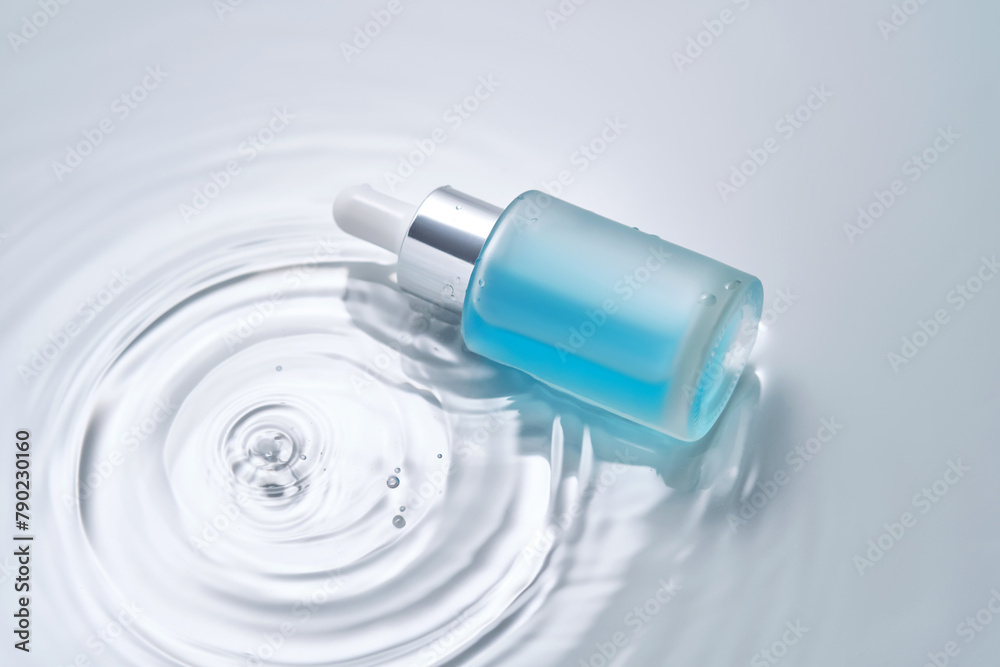Bottles of cosmetics with a dropper in water on a blue background. Bottles of cosmetics with a dropper in water on a blue background.