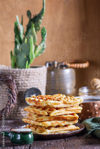 Obraz na płótnie Belgian waffles served with honey, cream and sai on a wooden background. Rustic style. w salonie