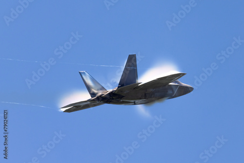 Tail view of a a F-22 Raptor at very high speed, with condensation clouds around the plane