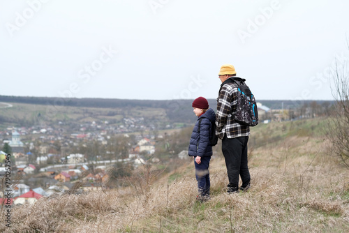 An elderly man and his grandson on a hill looking at the landscape of the village. Happy family active outdoor. Nature walking
