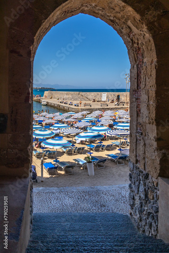 The busy beach of Cefalu shot through the arch leading to the old town