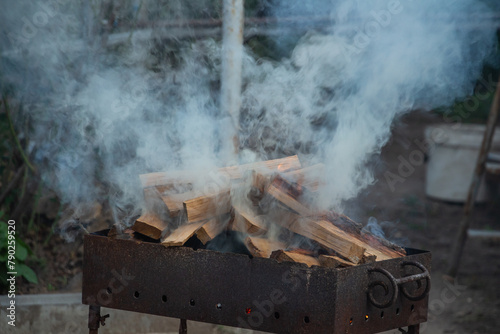 gray smoke background, firewood in the grill in a private yard, before ignition