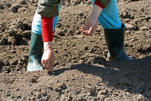 Close-up of the hands and feet of the person who puts the seeds in the soil.