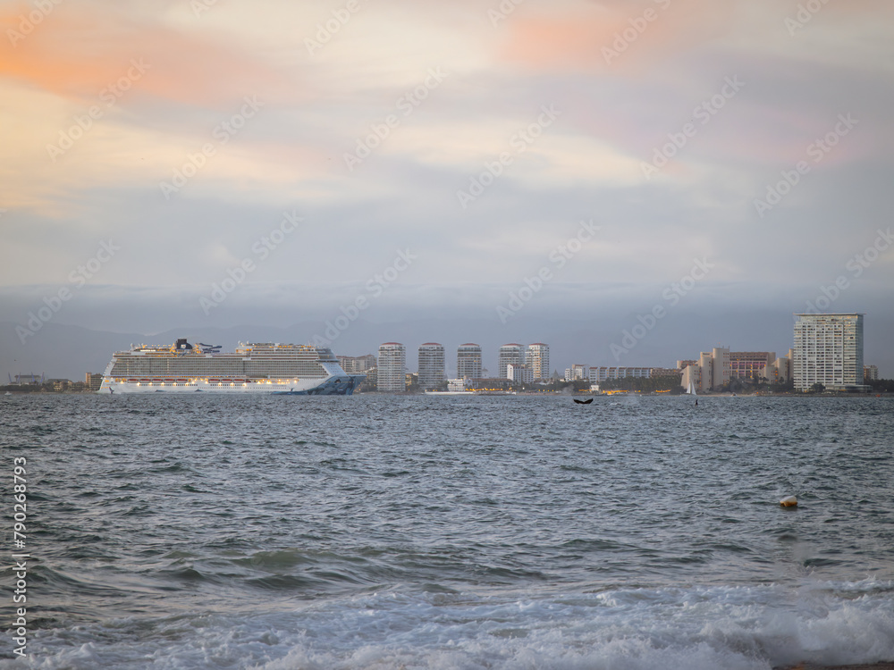 Whales breaching at sunset as cruise ship enter harbor in Puerto Vallarta near hotel zone.