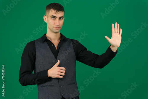 emotions of a handsome man guy on a green background chromakey close-up dark hair young man. spy photo
