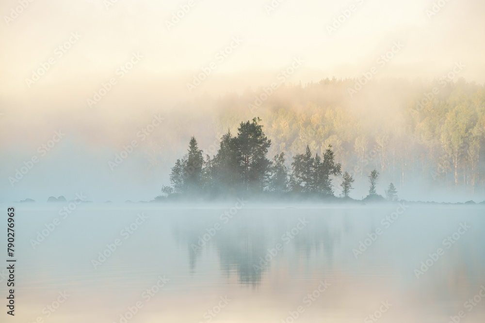 Sunrise over a tranquil lake with a small island, shrouded in mist Sunrise over a tranquil lake with a small island, shrouded in mist