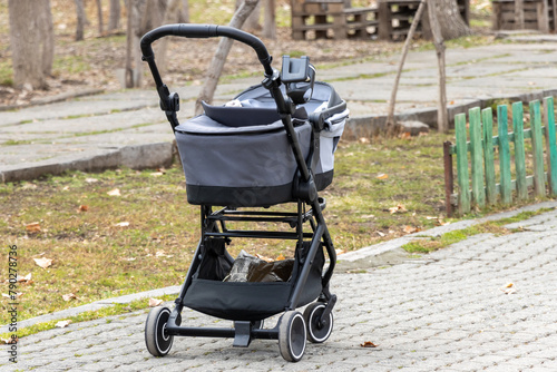 An empty black baby stroller in the park