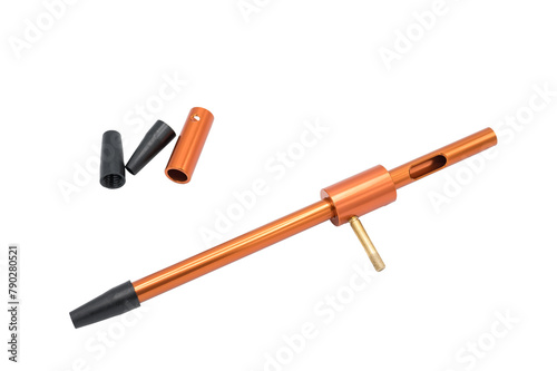 Detail of a universal guide for cleaning rifle and carbine barrels. It is an orange aluminum tube with interchangeable breech bolt lock and mouthpiece. It is on white background