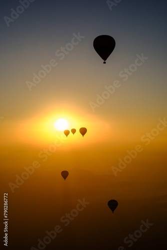 Sunrise in Morocco: A hot air balloon rises over desert dunes, illuminated by the dawn light.