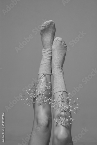 Beautiful women's legs with flowers, front view. Women's feet in socks with gypsophila flowers. Beauty and health of women's feet