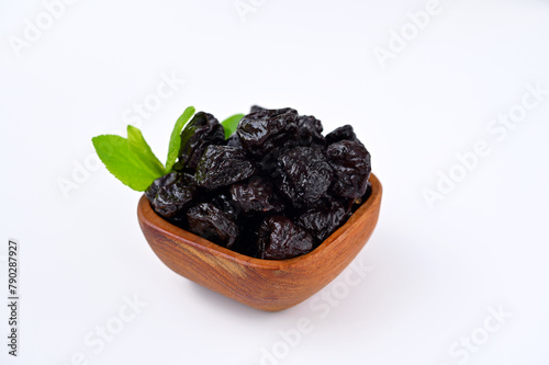 natural dried prunes in wooden bowl isolated on white background