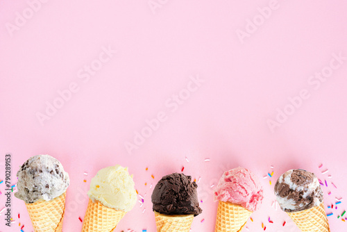 Ice cream cone bottom border over a pink background. Chocolate, strawberry and vanilla flavors. Copy space.