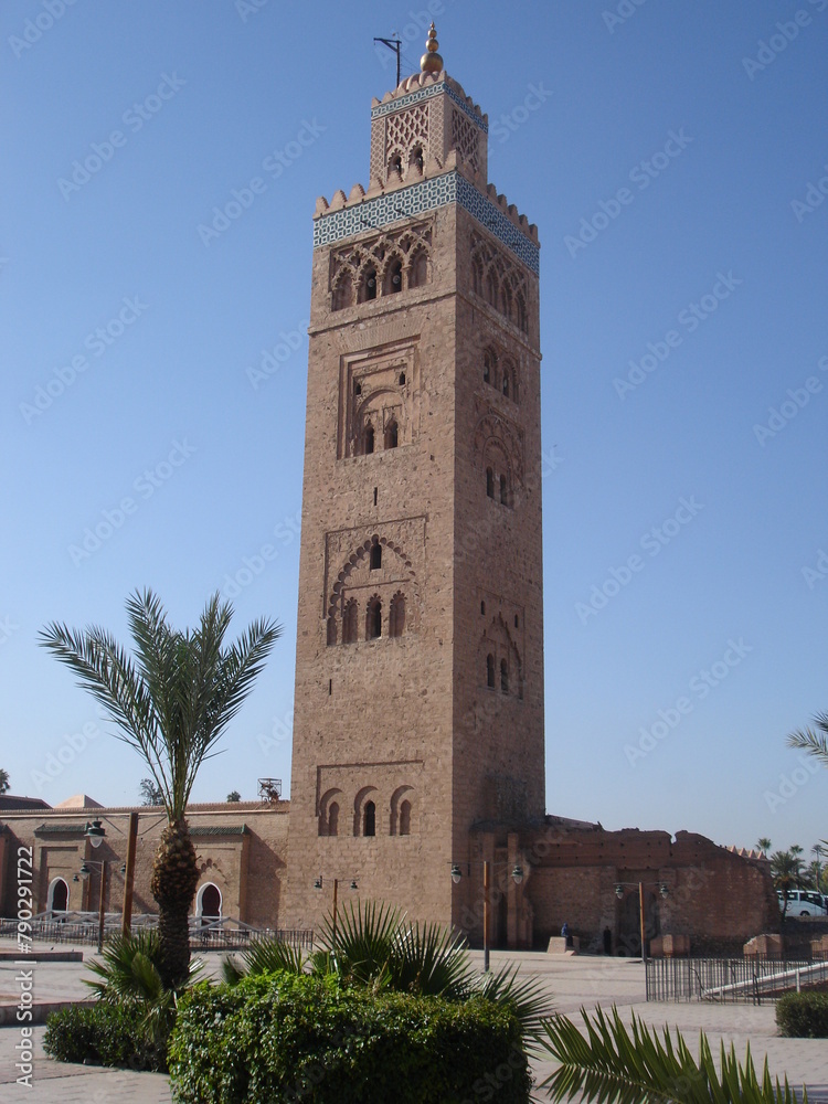 Image of the Kutubiyya Mosque in Marrakesh in early afternoon light set against a deep blue sky.