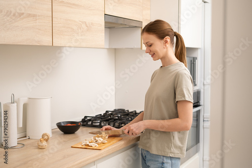 A young woman cooks in a bright and cosy kitchen. A girl chopping vegetables in her flat