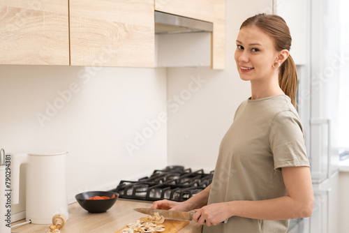 A young woman cooks in a bright and cosy kitchen. A girl chopping vegetables in her flat