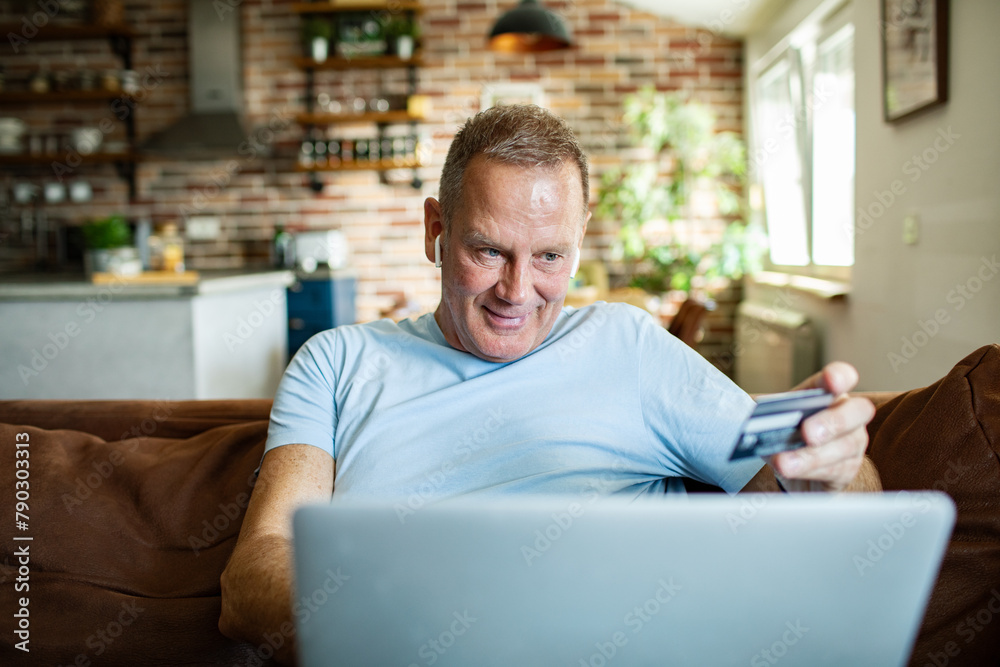 Middle aged man with credit card shopping online at home Middle aged man with credit card shopping online at home